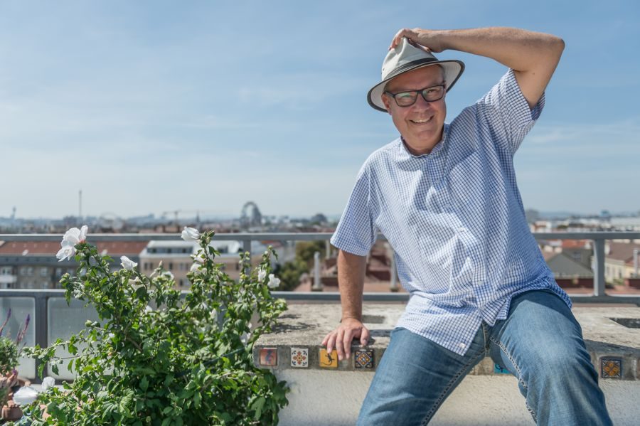 Johannes C. Hoflehner mit Hut auf einer Dachterrasse über Wien